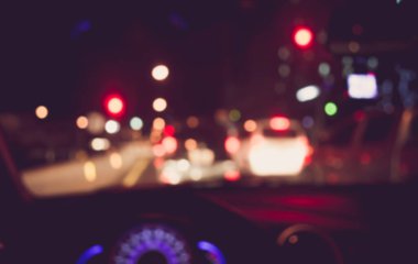 Arka plan kullanımı için gece vakti araba kullanan insanların klasik ton bulanık görüntüsü. (içeriden fotoğraf çek)