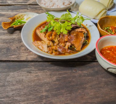 Tayland usulü domuz budu yahnisi (Kao Kha Moo) ve ahşap tabakta pirinç.