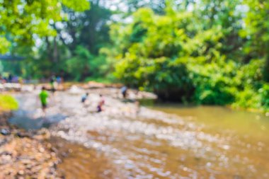 Gün içinde güzel bir nehirde oynayan bir grup insanın bulanık görüntüsü. .
