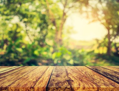 Ahşap tablo ve arkaplan kullanımı için güneş ışınları olan yeşil ağacın soyut Bokeh 'inin bulanık görüntüsü.