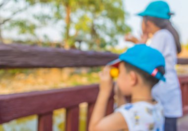 Arka plan kullanımı için dürbünü tutan elleri olan parkta küçük bir çocuğun bulanık görüntüsü..