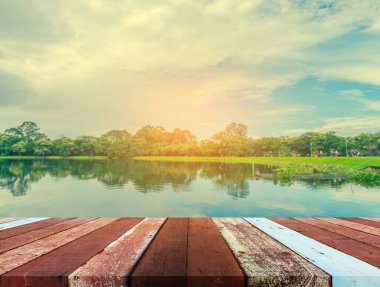 Eski ahşap masa ve yağmurlu gökyüzü ve arka planda dağ ile gölün klasik tonu.