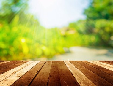 Ahşap tablo ve arkaplan kullanımı için güneş ışınları olan yeşil ağacın soyut Bokeh 'inin bulanık görüntüsü.