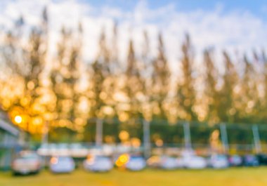 Yeşil bahçedeki otoparkın bulanık görüntüsü ve arka plan kullanımı için mavi gökyüzü.