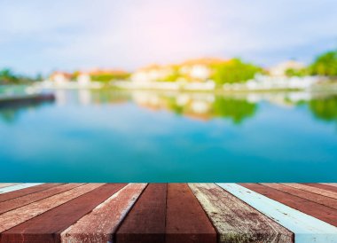 Ahşap iskele ya da gölün bulanık görüntüsü ve arka planda berrak gökyüzü olan eski ahşap bir masa.