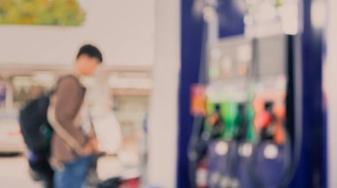 Arka plan kullanımı için gündüz vakti benzin istasyonunda bisikletli insanların bulanık görüntüsü.