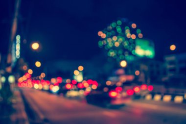 Gece vakti arka planda havai fişeklerle caddede araba görüntüsü bulanık.