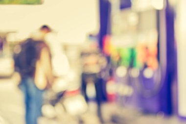 Arka plan kullanımı için gündüz vakti benzin istasyonunda bisikletli insanların bulanık görüntüsü.