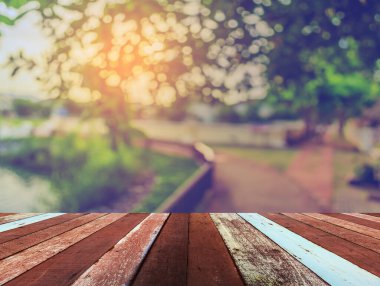 Ahşap iskele ya da arka planda gölün bulanık görüntüsü ve bokeh yeşili ağacı olan eski bir ahşap masa.