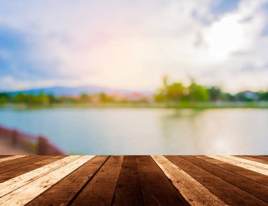 Ahşap iskele ya da arka planda gölün ve günbatımı görüntüsü olan eski ahşap bir masa.