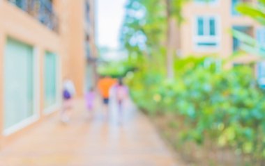 Arka plan kullanımı için yeşil bahçeye kadar açık alanda yürüyen insanların bulanık görüntüsü .