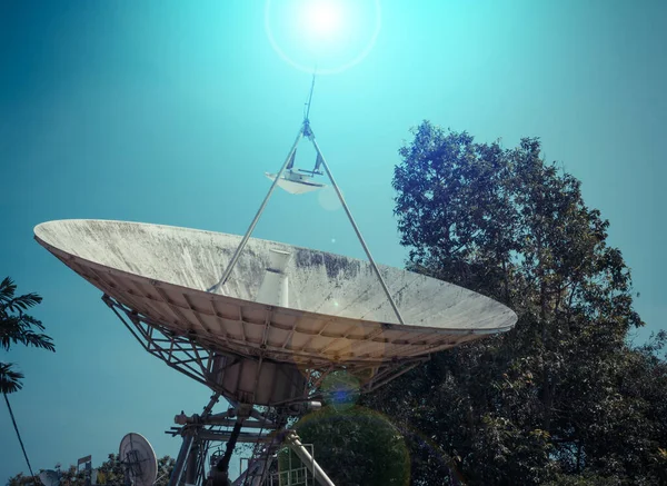 vintage tone image of large satellite dish and blue sky in background.