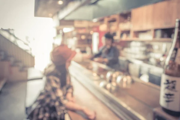 blur image of japan restaurant and lady customer waiting for her meal for background usage.