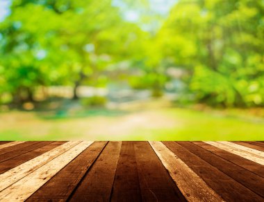 Ahşap tablo ve arkaplan kullanımı için güneş ışınları olan yeşil ağacın soyut Bokeh 'inin bulanık görüntüsü.