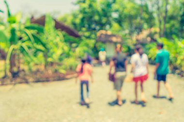 Arka plan kullanımı için yeşil parkta güneşli bir günde sokakta yürüyen bulanık insanların klasik ton görüntüsü .