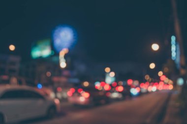 Gece vakti arka planda havai fişeklerle caddede araba görüntüsü bulanık.