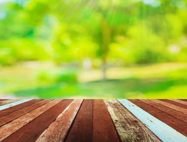 Ahşap tablo ve arkaplan kullanımı için güneş ışınları olan yeşil ağacın soyut Bokeh 'inin bulanık görüntüsü.