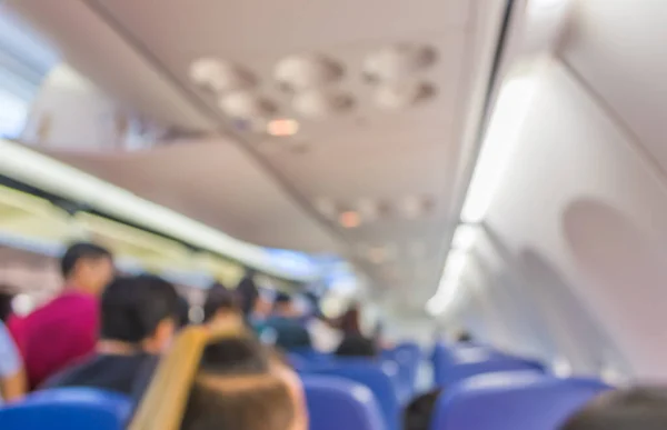 blur image of inside the airplane with people for background.