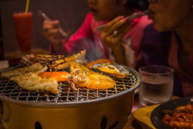 Demir rafta dilimlenmiş sığır eti ve kalamar ızgarası resmi .