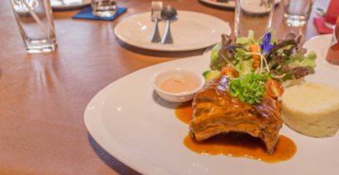 Güveç domuz pirzolası. Masada beyaz tabakta biftek.