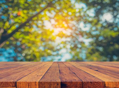 Arkaplan kullanımı için ahşap tablo ve yeşil ağaç bokeh 'in soyut bulanık resmi .