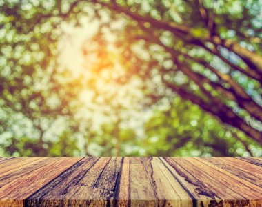 Arkaplan kullanımı için ahşap tablo ve yeşil ağaç bokeh 'in soyut bulanık resmi .