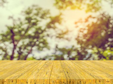 Arkaplan kullanımı için ahşap tablo ve yeşil ağaç bokeh 'in soyut bulanık resmi .