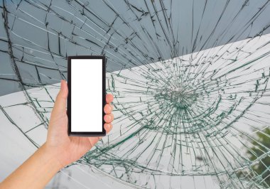 Beyaz ekranlı akıllı telefon ve kırık araba ön camlı erkek eli görüntüsü araba kazasında içeriden fotoğraf çekiliyor..