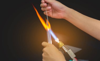 Cam üfleyici fabrikasındaki cam alevlerin üzerindeki el yapımı cam çubuğu yakın çekim görüntüsü. (alev üfleyici kafa odaklanın)