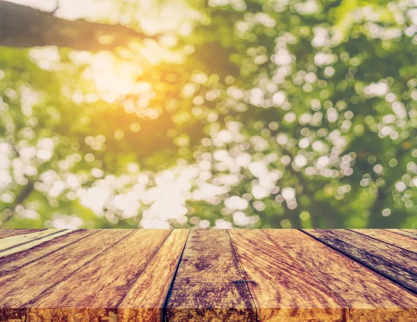 Arkaplan kullanımı için ahşap tablo ve yeşil ağaç bokeh 'in soyut bulanık resmi .