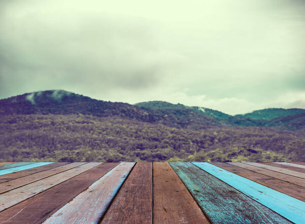 дерево стол и винтажный тон размытие изображения зеленой горы в фоновом режиме .