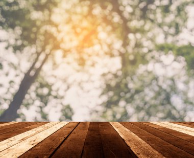 Arkaplan kullanımı için ahşap tablo ve yeşil ağaç bokeh 'in soyut bulanık resmi .