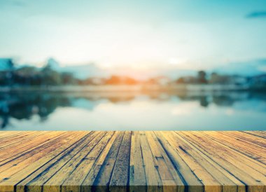Ahşap masa ve klasik ton gölün arka planda gün batımı gökyüzü ile bulanık görüntüsü .
