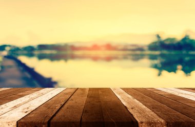 Ahşap masa ve klasik ton gölün arka planda gün batımı gökyüzü ile bulanık görüntüsü .