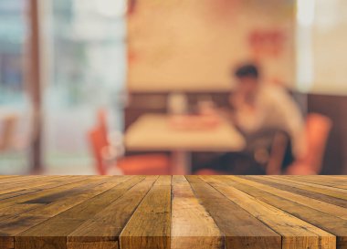 vintage tone image of selective focus on surface of wood table and blur restaurant or cafe for background usage.