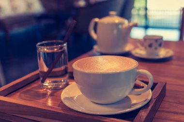vintage tone image of glass coffee cup on table in cafe.
