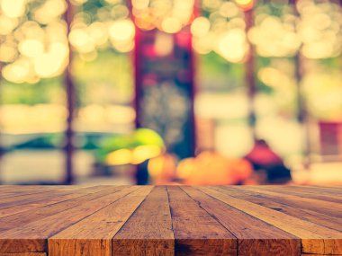 image of wood table and blur restaurant or coffee shop on day time with bokeh for background usage . (vintage tone)