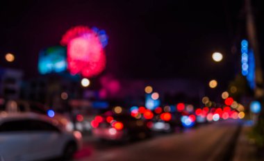 Gece vakti arka planda havai fişek olan caddedeki arabanın bulanık görüntüsü.