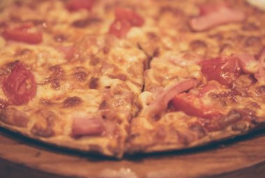 vintage tone image of ham and cheese pizza on table.