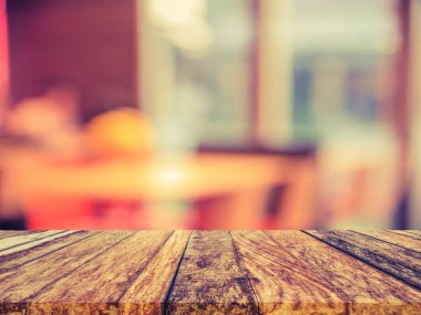 vintage tone image of selective focus on surface of wood table and blur restaurant or cafe for background usage.