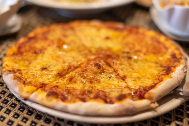 Masadaki peynirli pizzanın sıcak tonlu görüntüsü.