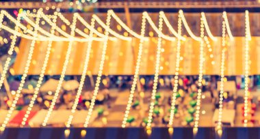 vintage tone abstract blur image of night festival in city with bokeh of light bulb.