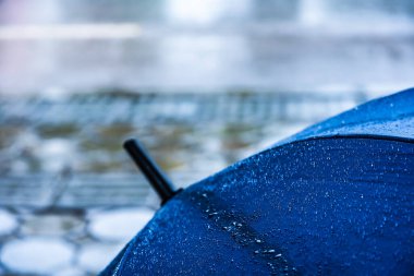 Yolun yakınındaki yağmurda yere konmuş mavi şemsiyenin klasik ton görüntüsü.
