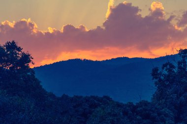 vintage tone image of sun crepuscular ray(beam) on the sky on day time with mountain for background usage.