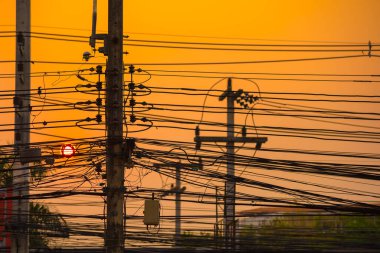 silhouette shot image of high voltage electric wire in city with sun on sunset sky in background.(focus on wire)