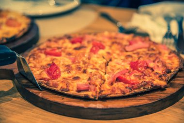 vintage tone image of ham and cheese pizza on table.