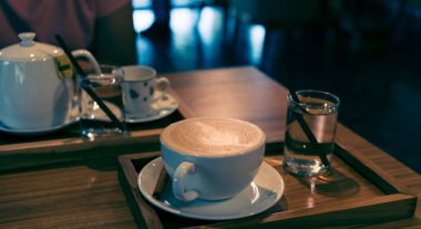 vintage tone image of glass coffee cup on table in cafe.