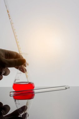 hand holding Lab glassware on glass table with warm and white tone background.