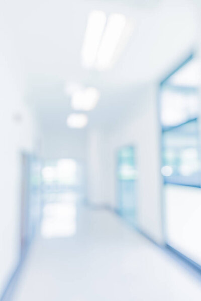 Абстрактно размытое синим тоном изображение ярких и чистых окон, дверей и стен в современном офисном здании в дневное время для фонового использования. (вертикаль)