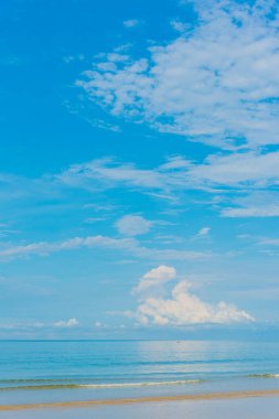 Üzerinde deniz ve bulutlu mavi gökyüzü var. (dikey)